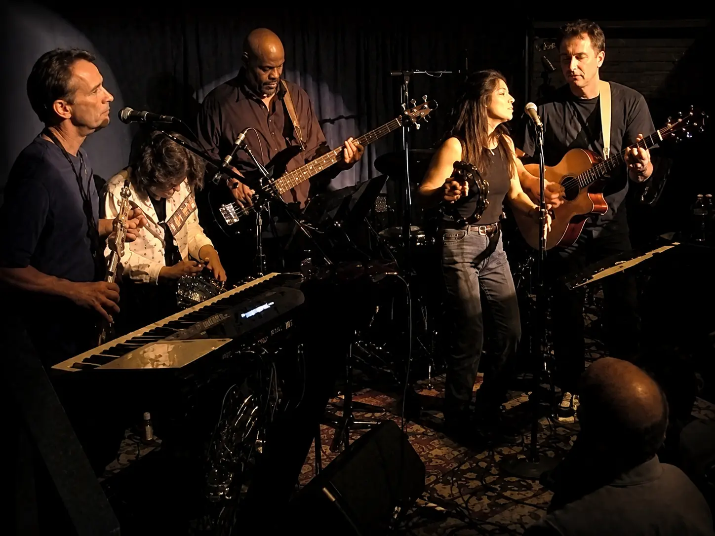 A four-piece band performing together in a cosy indoor setting